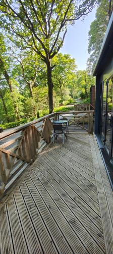 a wooden deck with a bench and a picnic table at Aberdunant Hall Holiday Park in Porthmadog
