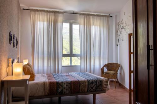 1 dormitorio con 1 cama y ventana con silla en La Tendera by #cherrygredos en El Arenal