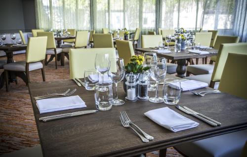 a dining room with tables and chairs with glasses and napkins at Mercure Bristol North The Grange Hotel in Bristol