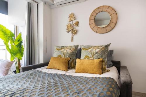 een slaapkamer met een bed met gele kussens en een spiegel bij Le Petit Pradignac Croisette - Connect Property in Cannes