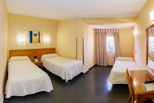 メリダにあるHotel Zeusのベッド2台とデスクが備わるホテルルームです。