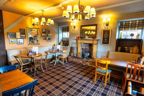 a restaurant with tables and chairs and a fireplace at The Lindisfarne Inn - The Inn Collection Group in Beal