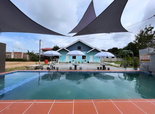 una piscina con una casa en el fondo en Membunga Village, en Kota Bharu