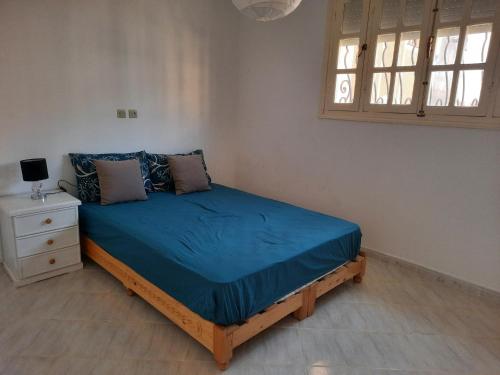 a bedroom with a bed with a blue comforter and a window at Ninasaidia in Saïdia