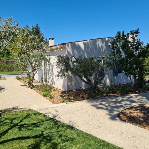 un bâtiment blanc avec des arbres à côté d'un trottoir dans l'établissement Très joli mazet Piscine privée Beau jardin clôturé Entièrement privatisé 5' à pied du centre, à Saint-Rémy-de-Provence
