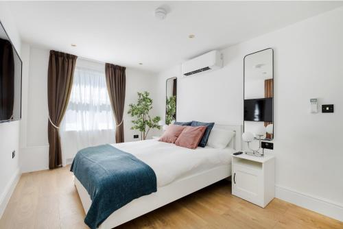 a white bedroom with a large bed and a window at Luxury 1 Bedroom Apartment in Central London in London