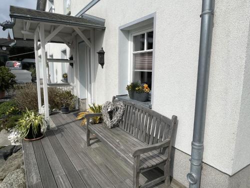 un banco de madera sentado en el porche de una casa en Villa Seestern - Ferienhaus mit Meerblick, en Sassnitz