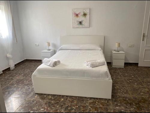 a white bedroom with a bed and two night stands at Bonita casa en Bolonia in Bolonia