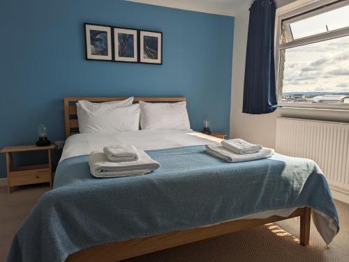 a blue bedroom with a bed with two towels on it at Apartment with a view, perfect for breaks and WFH in Plymouth