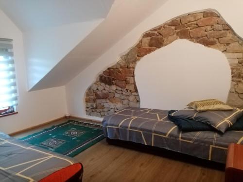1 dormitorio con cama y pared de piedra en Agroturystyka Camp4x4 en Nosów