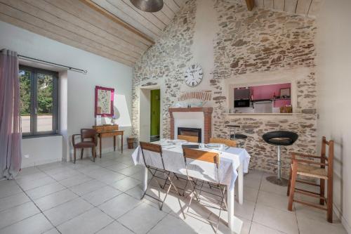 un salon avec une table et un mur en pierre dans l'établissement Longère rénovée à 500m du Centre de Pornic pour 4, à Pornic