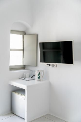 a white desk with a tv on a white wall at Vogue Suites in Oia