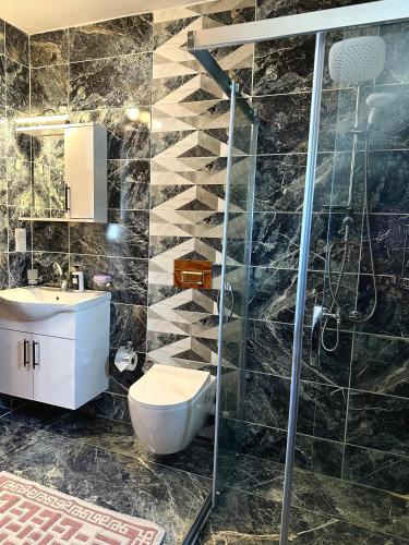 a bathroom with a shower and a toilet and a sink at Villa Misli - red/ green in Dalyan