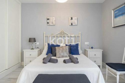 1 dormitorio con cama blanca y almohadas azules en Koti Rentals - El patio de Cervantes, en Fuengirola