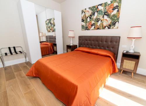 ein Schlafzimmer mit einem Bett mit einer orangefarbenen Tagesdecke in der Unterkunft Les Suites di Adi Luxury Apt in Bari