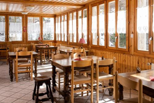a restaurant with wooden tables and chairs and windows at Aiguille de La Tza in Arolla