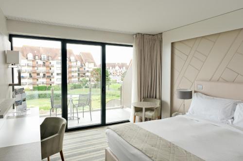 a hotel room with a bed and a large window at Thalazur Cabourg - Hôtel & Spa in Cabourg