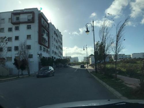 丹吉爾的住宿－Appartement Familial Proche Aeroport Bab Andalous Tanger，停在大楼旁的街道上的汽车