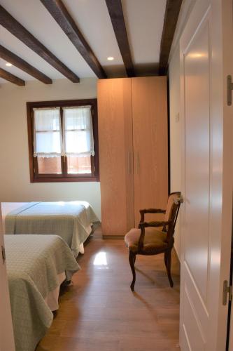 a bedroom with two beds and a chair and a window at Peritxenea Landa Apartamentuak in Lesaka