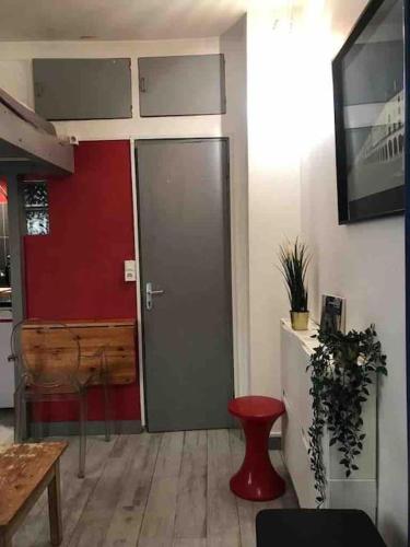 une pièce avec une porte avec un tabouret rouge et une table dans l'établissement Studio Marais Saint Paul, à Paris