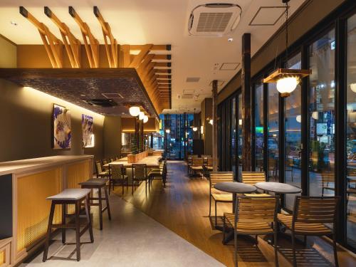 a restaurant with tables and chairs and windows at Akabane Holic Hotel in Tokyo