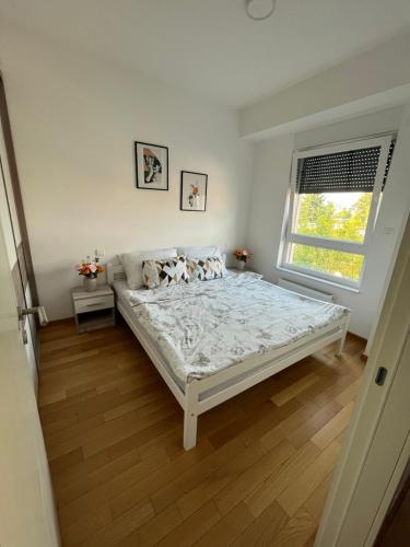 a white bedroom with a bed and a window at Apartmani Kastel in Banja Luka