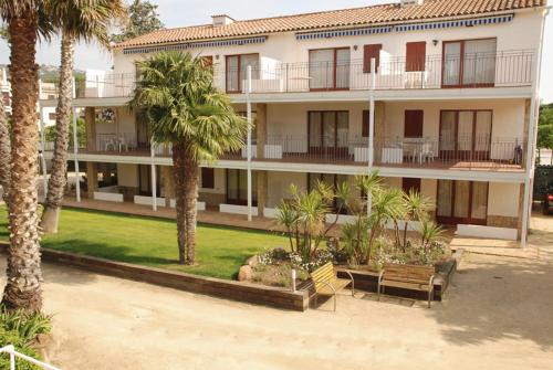 an apartment building with palm trees in front of it at Apartaments Margarita Sabina Pinell in Platja d'Aro