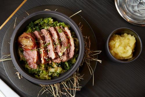 a bowl of food with meat and greens and a bowl of mashed potatoes at Maison Rouge Strasbourg Hotel & Spa, Autograph Collection in Strasbourg