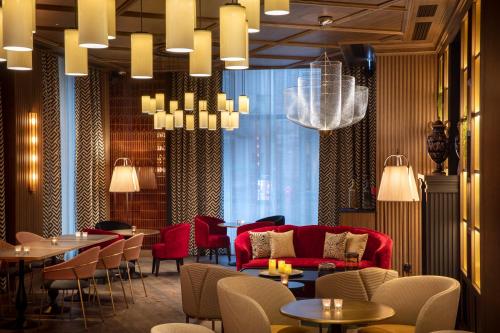 een restaurant met een rode bank en tafels en stoelen bij Maison Rouge Strasbourg Hotel & Spa, Autograph Collection in Straatsburg
