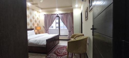 ein Schlafzimmer mit einem Bett, einem Stuhl und einem Fenster in der Unterkunft Hotel Daffodils in Rawalpindi