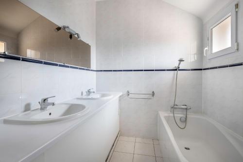 La salle de bains blanche est pourvue de 2 lavabos et d'une baignoire. dans l'établissement 600m de la plage - Maison pour 8 - Jardin, à Pornichet