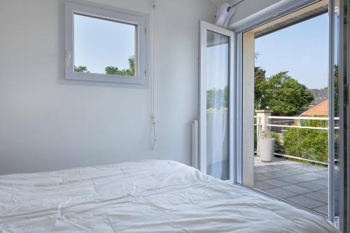 une chambre blanche avec un lit et un balcon dans l'établissement 600m de la plage - Maison pour 8 - Jardin, à Pornichet