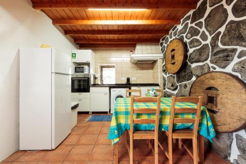 a kitchen with a table and chairs and a stone wall at Casas de Campo HousesInPico in Prainha de Baixo