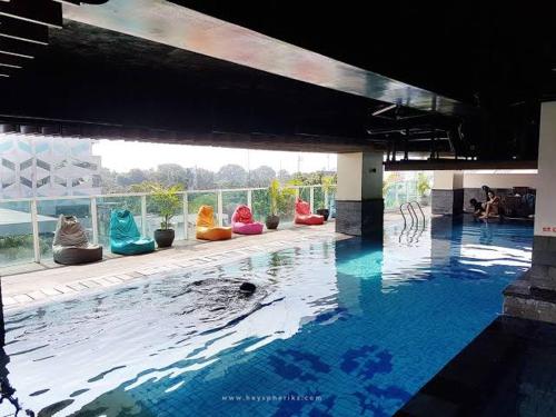 einen Pool mit bunten Stühlen im Wasser in der Unterkunft La Grande Merdeka Apartment in Bandung