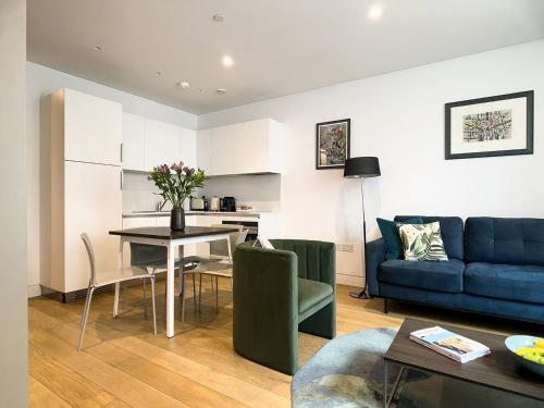 un soggiorno con divano blu e tavolo di Mirabilis Apartments - Bayham Street a Londra