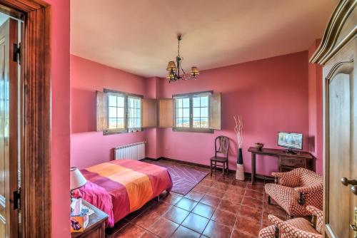 a bedroom with pink walls and a bed and a desk at Posada de Ajo in Ajo