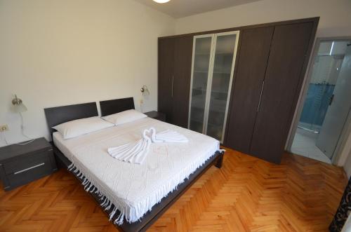 a bedroom with a white bed with a wooden floor at Apartments Ivetić in Kotor