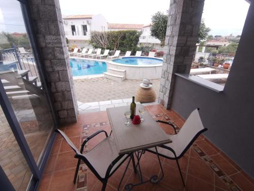 a table and chairs on a balcony with a pool at Taletos Apartments in Stoupa