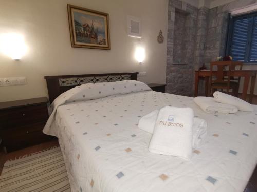 a bedroom with a white bed with two towels on it at Taletos Apartments in Stoupa