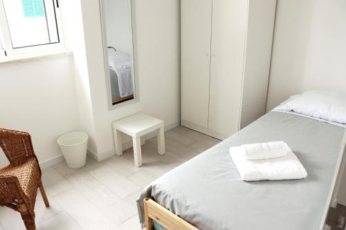 a small white bedroom with a bed and a chair at Casa do Bairro in Horta