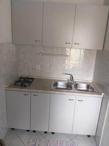 a kitchen with white cabinets and a sink at Direkt na moru - Bungalov in Šibenik
