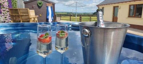 dos vasos de agua y un cubo con fresas. en Sunny Bank- Countryside Escape with Private Hot Tub and countryside views en Carmarthen