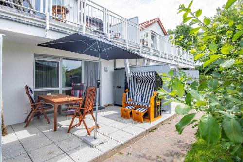 a patio with a table and chairs and an umbrella at Haus Seeblick Wohnung 11 "Blåkulle" in Wohlenberg