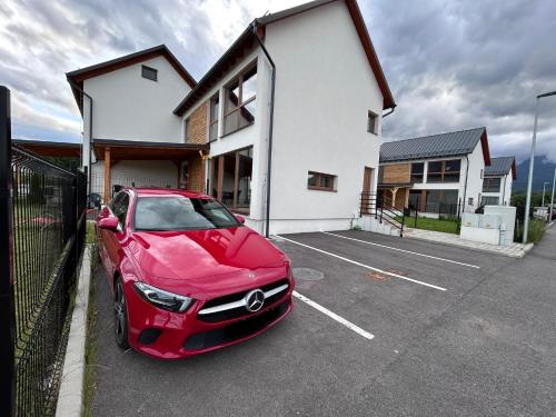 a red car parked in a parking lot in front of a house at Vila Luxury in Nová Lesná