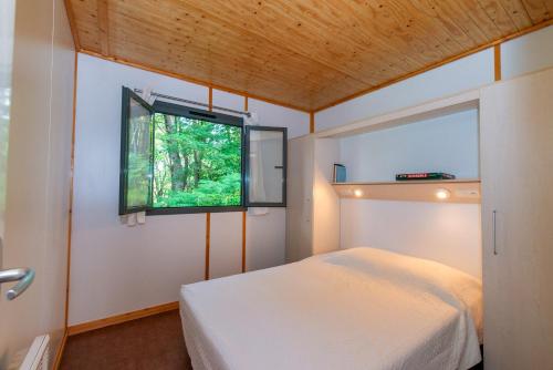 Schlafzimmer mit einem Bett und einem Fenster in der Unterkunft Camping de La Vernhe in Saint-Amans-des-Cots