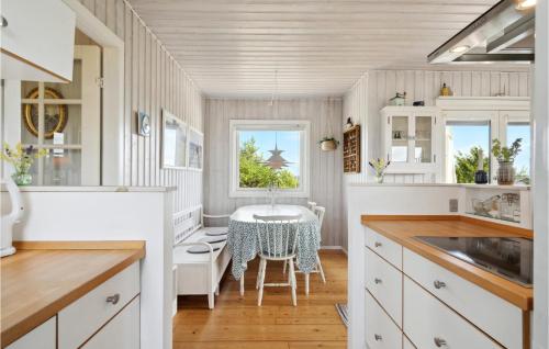 福堡的住宿－Beautiful Home In Faaborg With Kitchen，厨房配有白色橱柜和桌椅