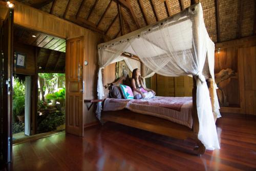 dos chicas acostadas en una cama en un dormitorio en Rohotu Fare en Bora Bora