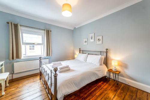 a bedroom with a bed with white sheets and a window at Pass the Keys Stylish newly renovated Victorian 2 bedroom house in Shrewsbury