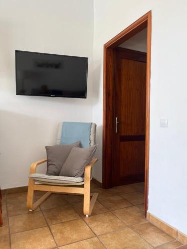 een stoel in een kamer met een televisie aan de muur bij Bungalows El Palmital - Adults Only in Playa del Inglés