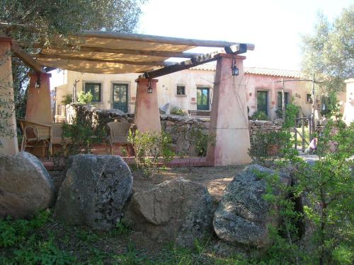 a house with a pergola and rocks in a yard at La MeSenda Rooms & Apartments in Arzachena
